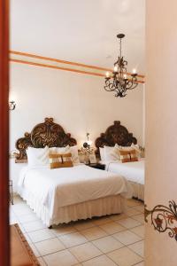 1 dormitorio con 2 camas y lámpara de araña en Los Pilares Hotel, en Oaxaca City