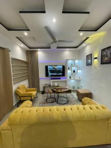 sala de estar con sofá amarillo y mesa en Entrée personnelle 2 chambres, en Cotonou