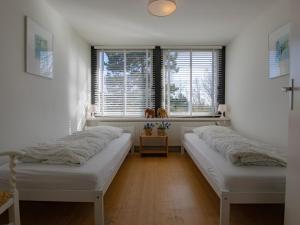 two beds in a room with two windows at Landhuis Duinzicht in Callantsoog