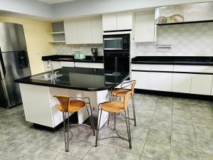 a kitchen with a black counter and three chairs at The Rainier Bed & Breakfast 5 in San José