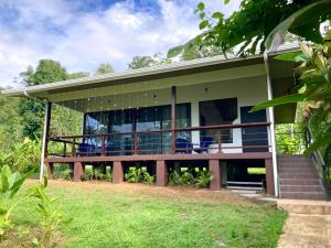 a house with a porch with blue chairs on it at Eden Corcovado in San Pedrillo