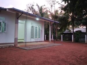 a small white house with a palm tree at Cosy Holiday Home in Jayarajapuraya