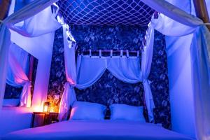 a bedroom with a canopy bed with blue and pink lighting at Tropical Jungle Loveroom Pau centre in Pau