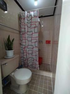 a bathroom with a toilet and a shower curtain at Green Valley Condo with View in Baguio