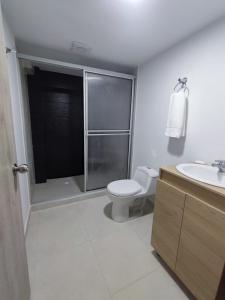 y baño con aseo, lavabo y ducha. en Hostal Ninfa del Mar, en Manizales