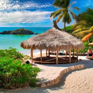 uma cabana de palha numa praia com uma palmeira em Nature Harmony Retreat in Tierra Bomba - Your Sustainable Escape 01 em Cartagena das Índias
