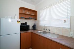 a kitchen with a white refrigerator and a sink at 24 Burswood Comfort Short Walk To Crown & Optus! - Superhog verification Required in Perth
