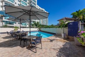 una mesa con sillas y una sombrilla junto a la piscina en TRYP by Wyndham Rio de Janeiro Barra Parque Olímpico, en Río de Janeiro