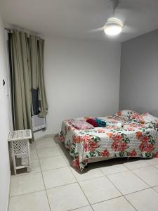um quarto com uma cama com um edredão floral em Praia em Lauro de Freitas