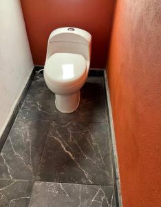 een badkamer met een wit toilet in een rode muur bij Casa De Campo in Acaxochitlán