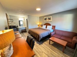 a hotel room with a bed and a couch at Ozark Inn & Suites in Ozark