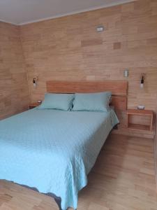 1 dormitorio con 1 cama con pared de madera en Altos de Llicaldad Lodge en Castro