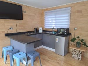 a kitchen with a counter with stools and a tv at Altos de Llicaldad Lodge in Castro