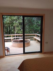 Zimmer mit einer großen Glastür mit Blick auf einen Hund in der Unterkunft Altos de Llicaldad Lodge in Castro