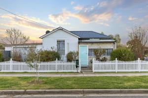 a white house with a white picket fence at Stylish Lake Albert Cottage, Wagga Wagga in Wagga Wagga