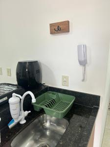 a kitchen sink with a green strainer next to a phone at Ap barato e perfeito insta thiagojacomo in Goiânia