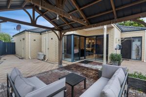 an outdoor patio with white couches and a wooden pergola at 13 Family Home In Morley Sleeps 6 Comfortably in Perth