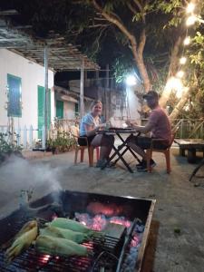 Due uomini seduti a un tavolo vicino a una griglia di OVi coffee farmstay Đà Lạt a Da Lat