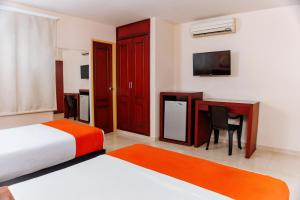 Dormitorio con cama, escritorio y TV en Hotel Luxor Cúcuta en Cúcuta