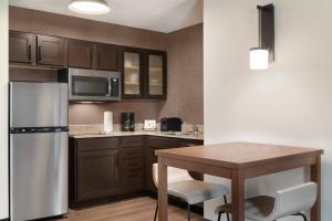 a kitchen with a table and a stainless steel refrigerator at Residence Inn Houston The Woodlands/Market Street in The Woodlands