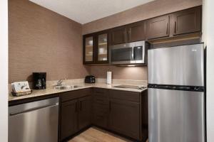 a kitchen with brown cabinets and a stainless steel refrigerator at Residence Inn Houston The Woodlands/Market Street in The Woodlands