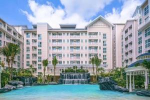 an apartment building with a waterfall in front of it at Grand Florida Beach condo in Na Jomtien