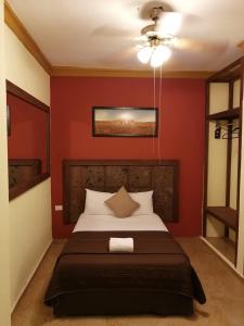 a bedroom with a bed with a red wall at Hotel Rinconada del Convento in Izamal