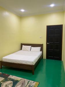 a bedroom with a bed with white sheets and a door at Fadlim Homestay in Padang Serai