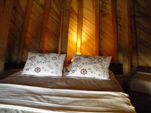 a bed with two pillows in a room with wooden walls at Moulin De Chez Renaud in Sousmoulins