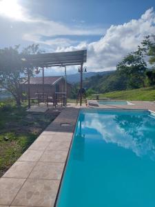 a swimming pool with a pergola next to a house at Cabaña Niraj in Cartago