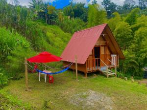 una pequeña casa con hamaca y techo rojo en Cabañas Villa Loe en Jardin