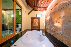 a bathroom with a tub and a stone wall at Kacha Resort & Spa, Koh Chang in Ko Chang