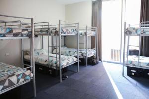 three bunk beds in a room with a window at Barkly Backpackers in Melbourne