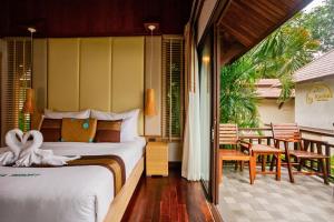 a bedroom with a bed and a balcony with a table at Kacha Resort & Spa, Koh Chang in Ko Chang
