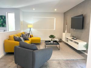 a living room with a yellow couch and a tv at 2 Chic Stylish Modern Family On Charles in Perth
