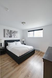 a white bedroom with a large bed and a window at Denis in Quebec City