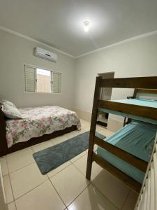 a bedroom with two beds and a bunk bed at Casa de Temporada Ferreira in Olímpia