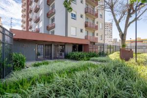 un edificio de apartamentos con césped alto delante de él en Likehome Connect, en Porto Alegre