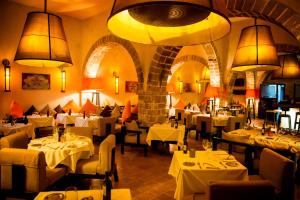 un restaurant avec des tables blanches, des chaises et des lumières dans l'établissement Madada Mogador, à Essaouira