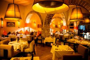 un restaurante con mesas blancas, sillas y luces en Madada Mogador, en Essaouira