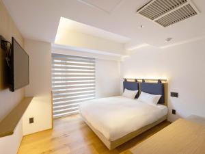 ein Schlafzimmer mit einem weißen Bett und einem Fenster in der Unterkunft hotel androoms Kyoto Shichijo in Kyoto