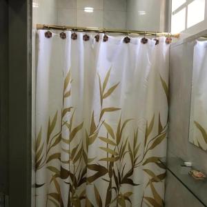 a shower curtain with a plant pattern in a bathroom at Kris Kross Apartment in Plymouth