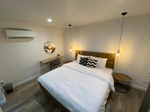 a bedroom with a large white bed and a desk at Cordia Residence Saladaeng in Bangkok