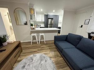a living room with a blue couch and a kitchen at Central Evans Wagga Apartments in Wagga Wagga