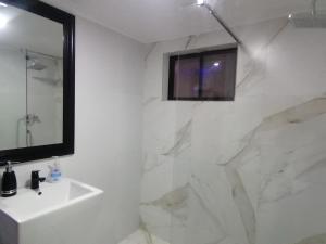 een witte badkamer met een wastafel en een spiegel bij casa entera con estacionamiento in Santiago