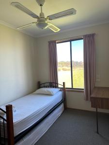 a bedroom with a bed with a ceiling fan and a window at Moana Beach Tourist Park in Moana