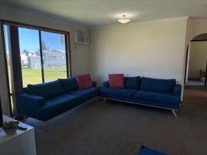 a living room with two blue couches and a window at Moana Beach Tourist Park in Moana