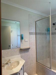 La salle de bains est pourvue d'un lavabo et d'une douche. dans l'établissement Moana Beach Tourist Park, à Moana