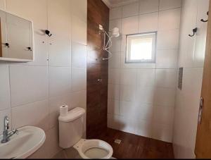 uma casa de banho com um WC, um lavatório e uma janela em Sítio em Atibaia em Atibaia