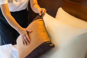 Una mujer está cortando una almohada en una cama en Lanta Thip House by Swiss-Belhotel - SHA Plus en Ko Lanta